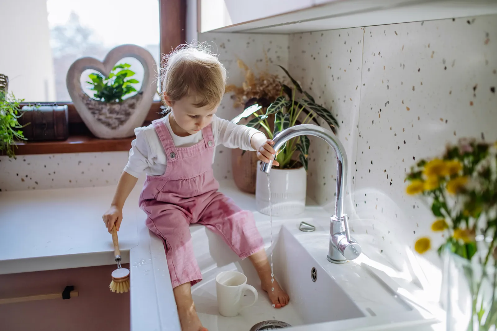Parent and child replacing an under-sink water filter together — annual filter replacement is the primary maintenance task
